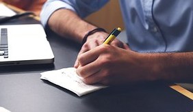 man writing with pen